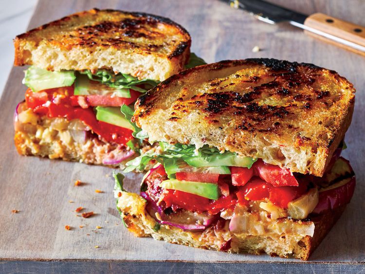 La receta definitiva de sándwich vegetariano Club cortado en rodajas en la tabla de cortar