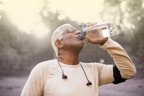 Foto de un hombre bebiendo agua mientras hace ejercicio.