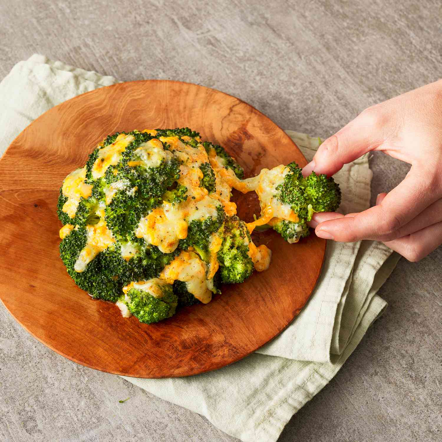 Foto de receta del brócoli con queso cheddar servido en una fuente.