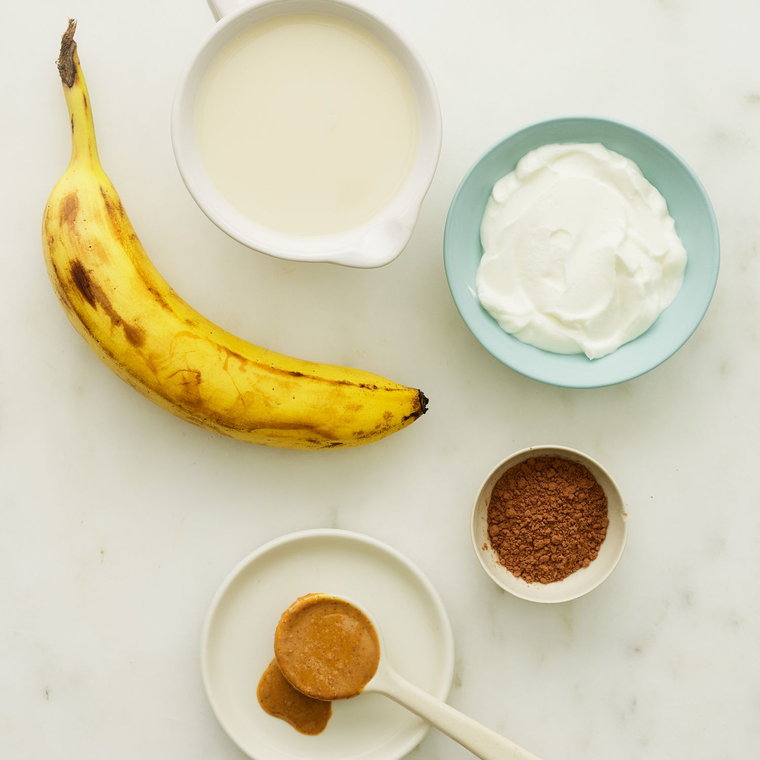 Un material de batido de proteína de mantequilla de mantequilla de chocolate y galletas con chispas de chocolate se sacuden en un lado blanco.
