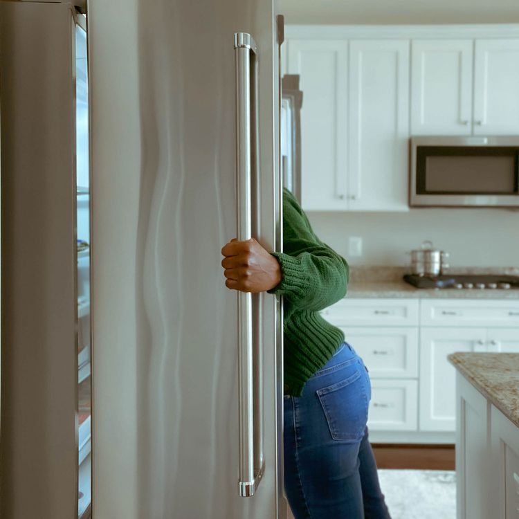 Una mujer que mira al refrigerador; cuando la privación del sueño, la hormona hambrienta disminuye. Cuando se aplica el estrés a esto, se pierde el equilibrio entre Grin (