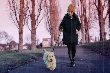 Una foto de una mujer paseando a su perro en una mañana de invierno.