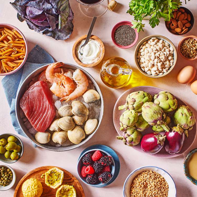 Alimentos dietéticos mediterráneos que contienen filete, camarones, bayas, alcachofas, yogurt, semillas, pastas, nueces, huevos y aceite de oliva