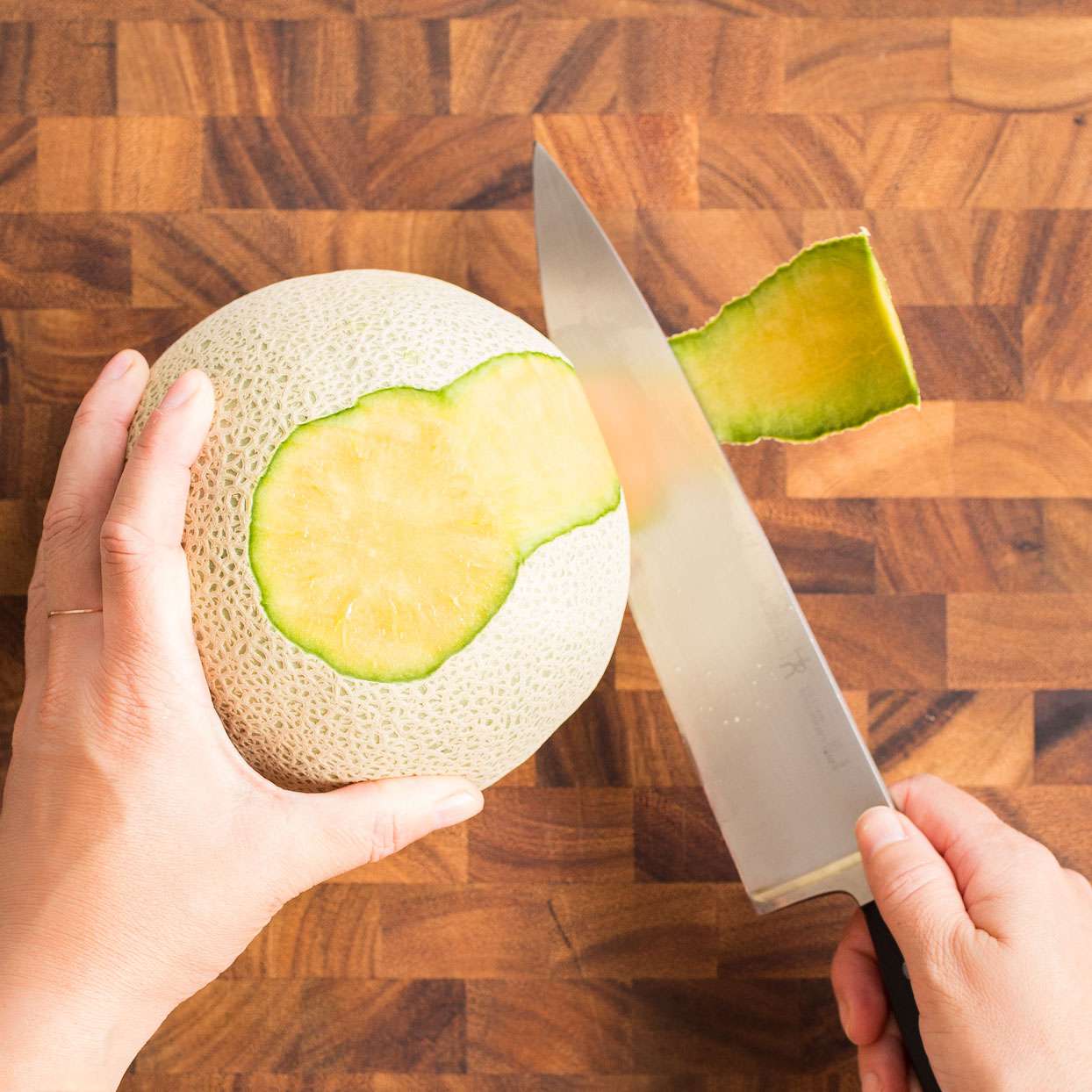 Corta la piel del melón con un cuchillo de cocina en una tabla de cortar de madera