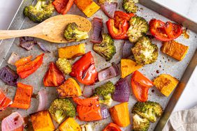Foto de la receta de coloridas verduras de hojas asadas dispuestas en una bandeja para hornear galletas.