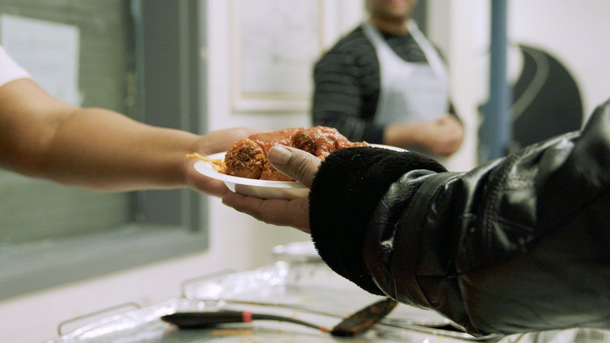 La mano que sostiene el plato de comida se extiende para pasárselo a otra mano.