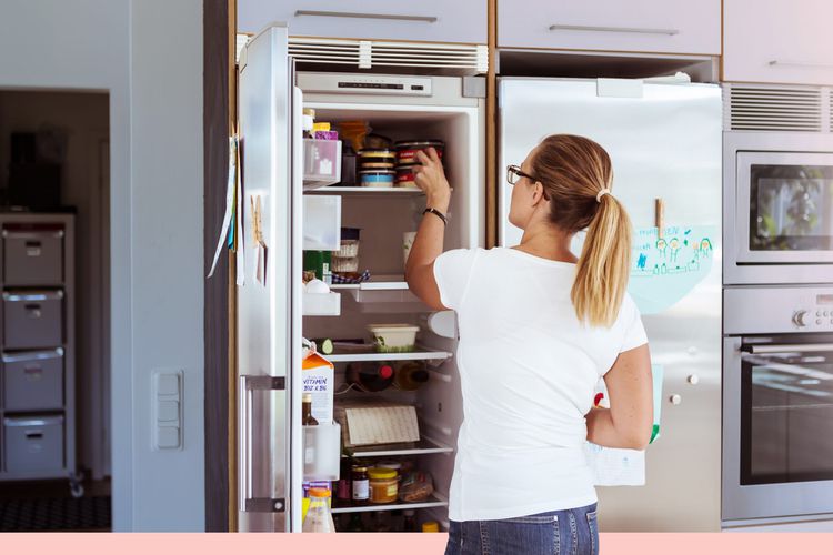 Vista trasera de una mujer mirando el refrigerador mientras está de pie en la cocina.