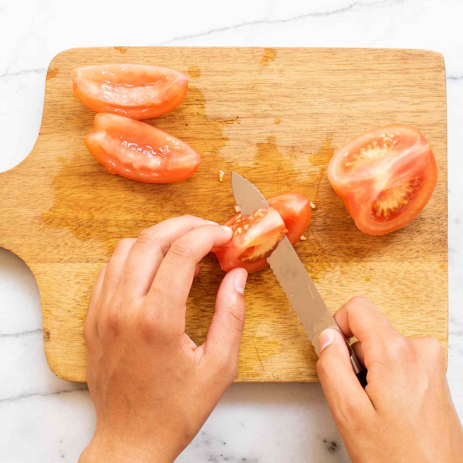 Mano usando un cuchillo para cortar un tomate en cubitos sobre una tabla de cortar