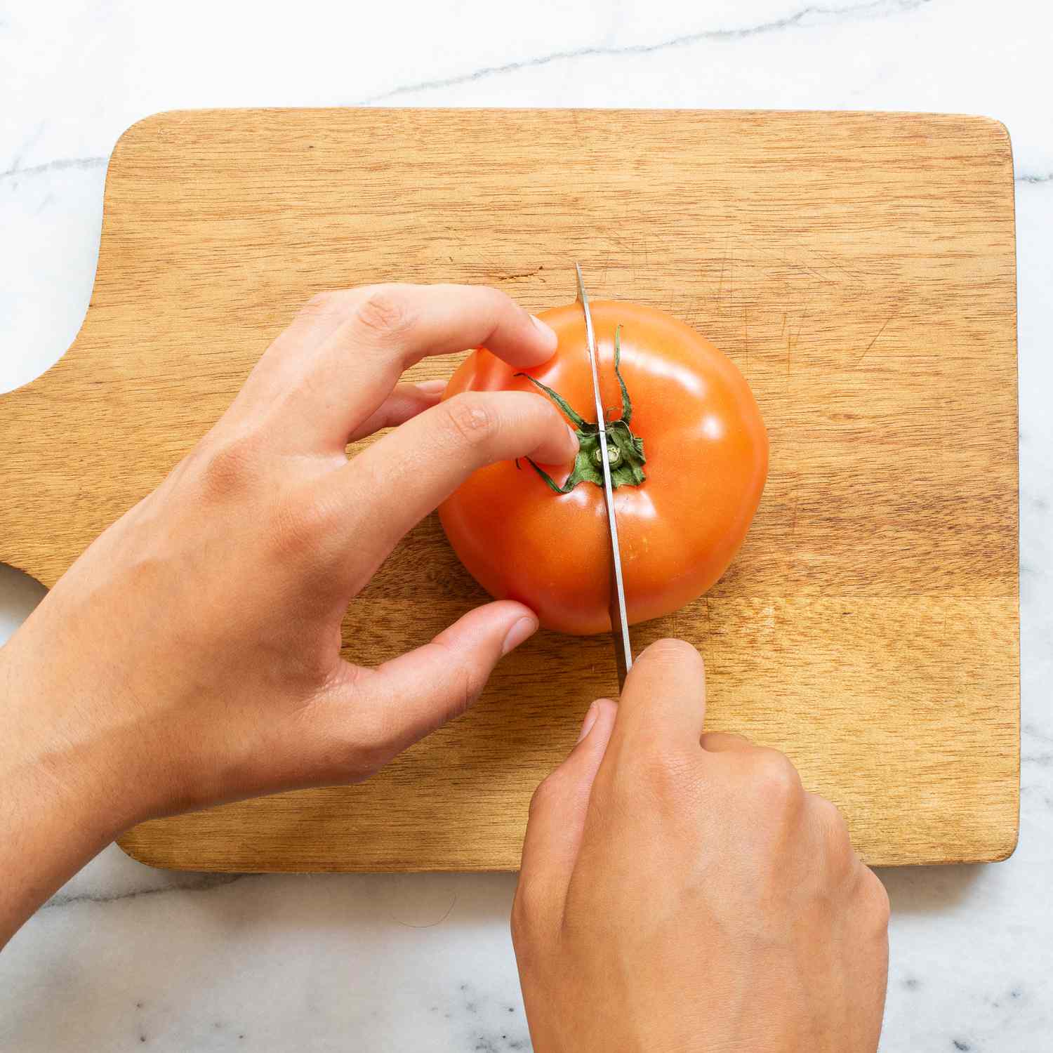 Cortar tomates a mano con un cuchillo sobre una tabla para cortar
