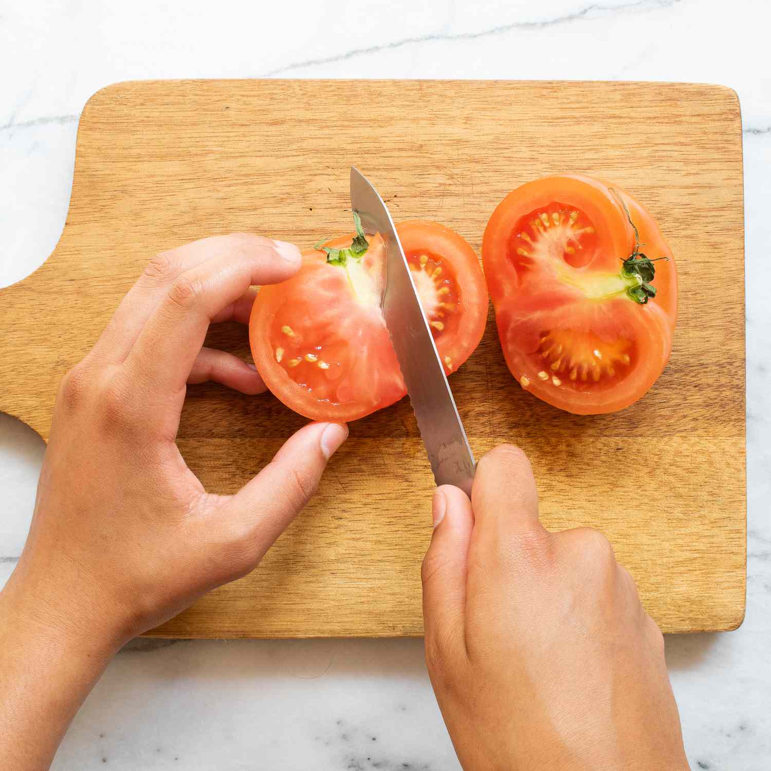 Cortar tomates a mano con un cuchillo sobre una tabla para cortar