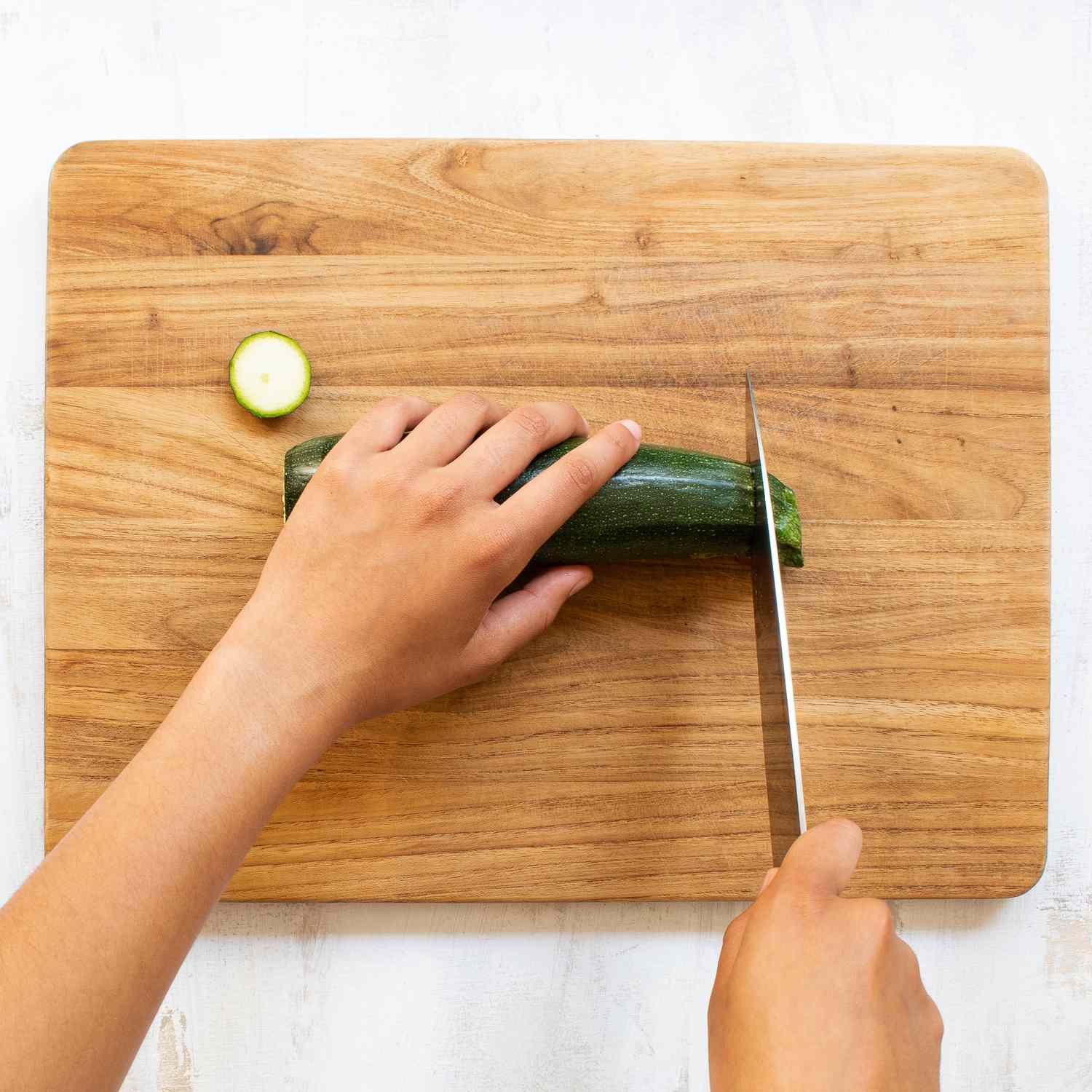 Cortar calabacines a mano con un cuchillo sobre una tabla de cortar de madera