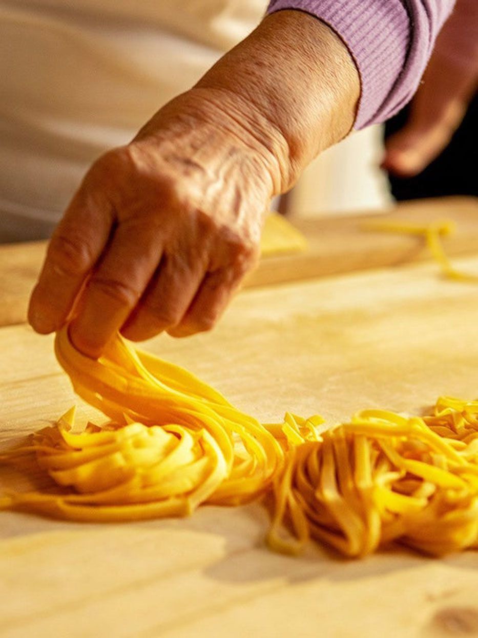La mano de una anciana se cierra mientras hace pasta