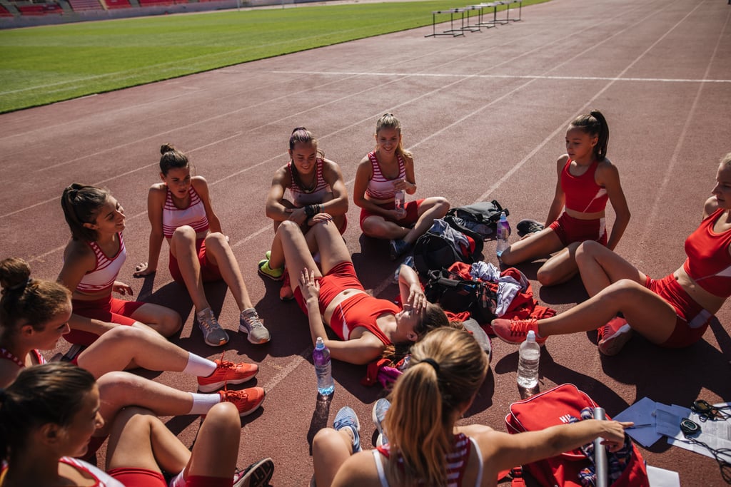 El equipo de Joven Atletismo disfruta de un rato después de la práctica en el estadio deportivo.