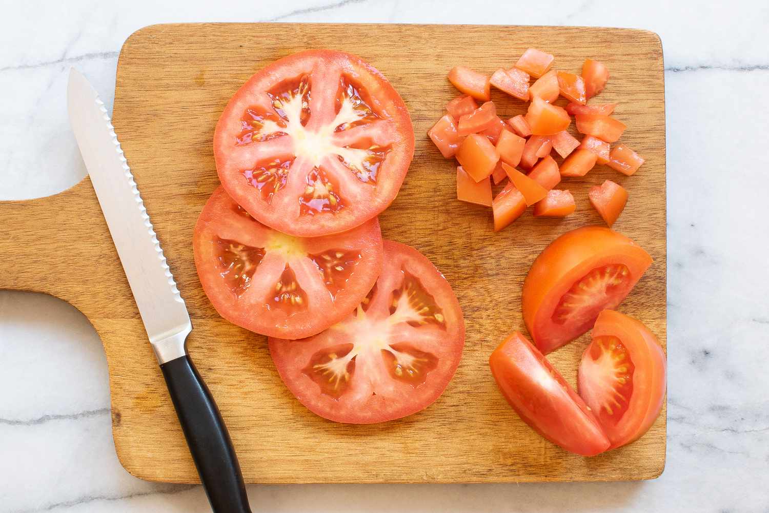 Una tabla de cortar con cuchillos y varias formas diferentes de cortar tomates.