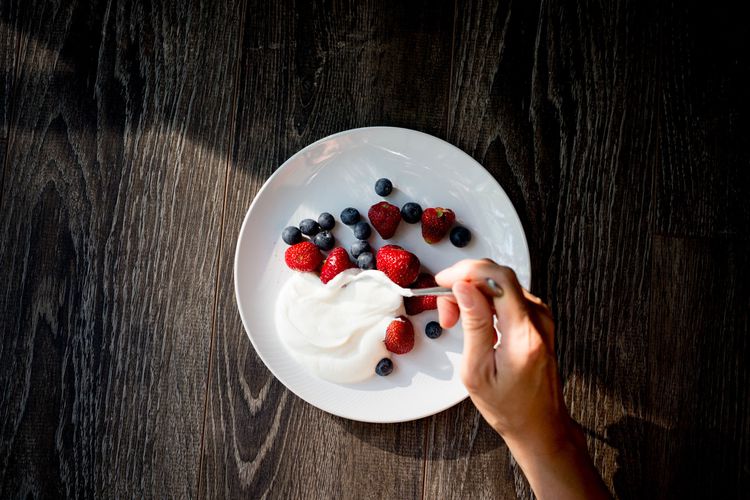 Fotografía aérea de yogurt y bayas colocadas en una mesa de madera.